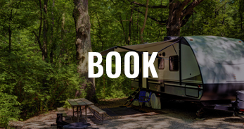 small camper RV by a picnic table with overlay text that says "book"