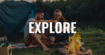 young man and woman in front of campfire, tent behind them, text overlay says "explore"