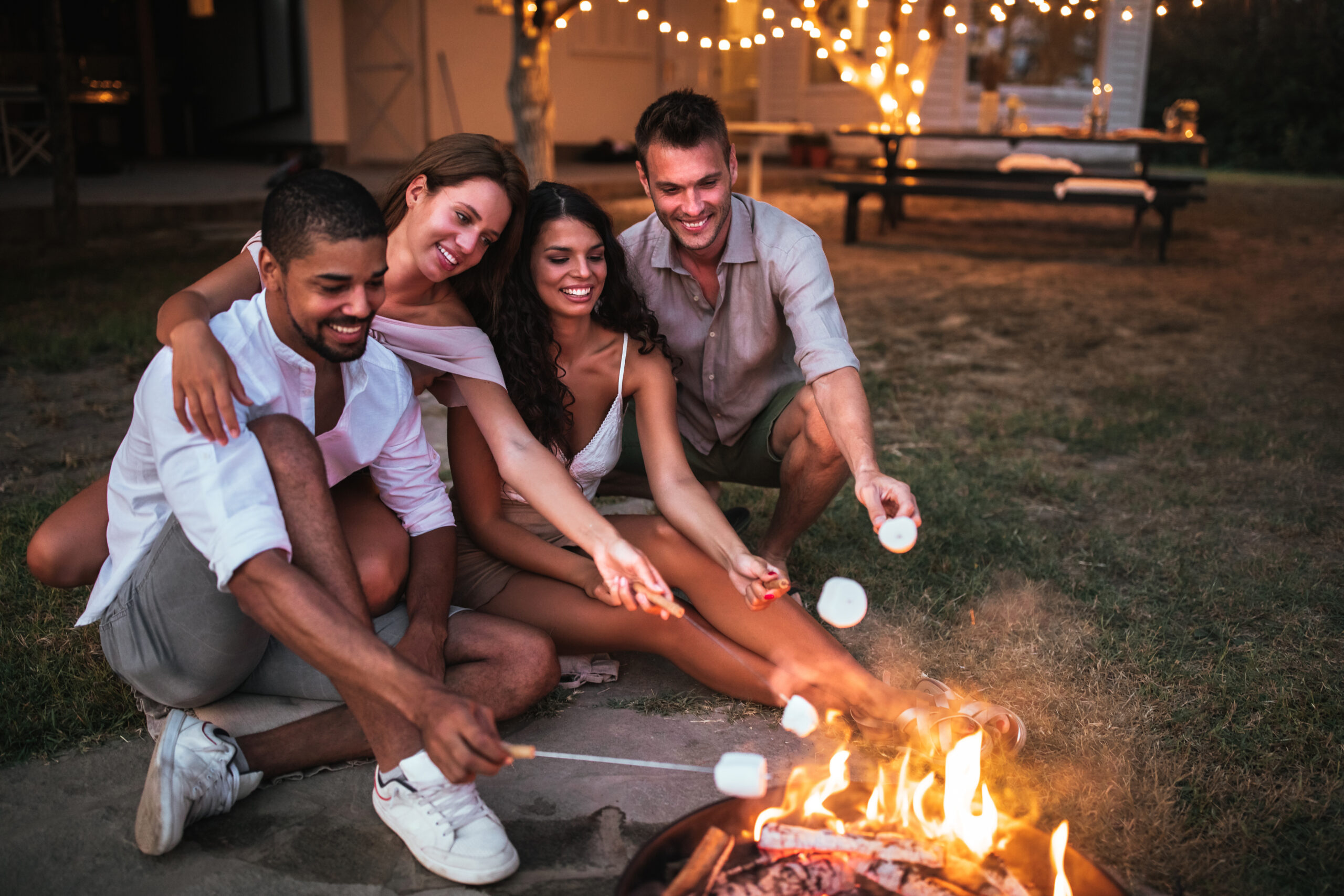 two couples roasting marshmallows over campfire