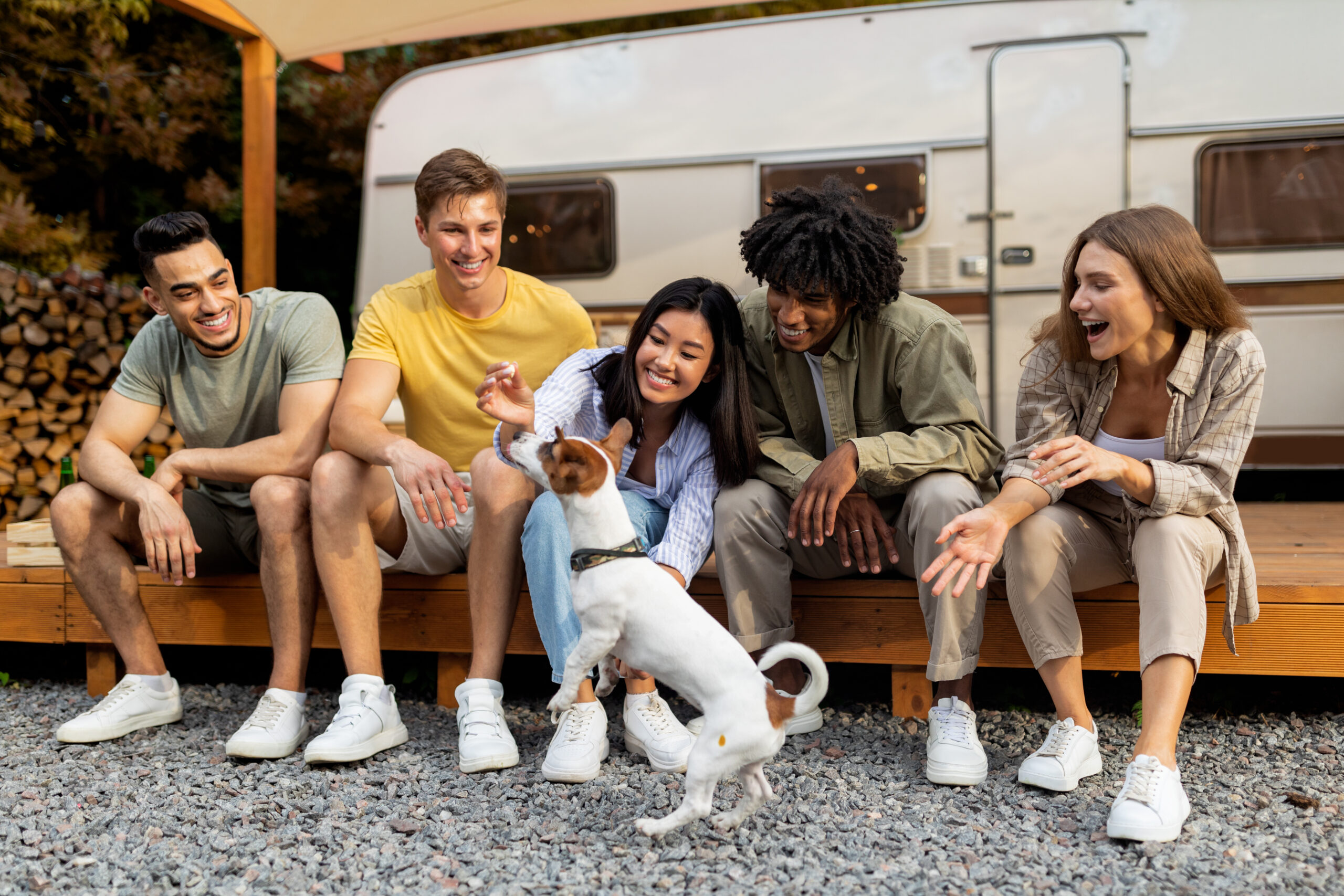 family sits by camper with dog