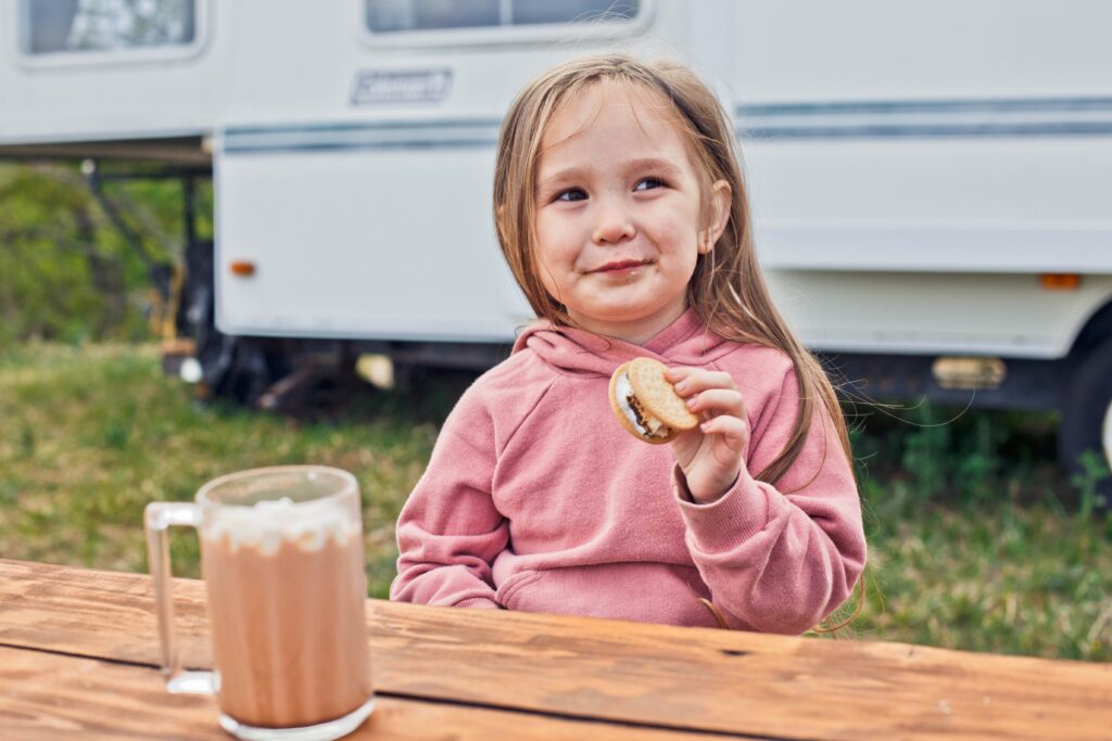little-girl-eating-s'more-in-front-of-RV