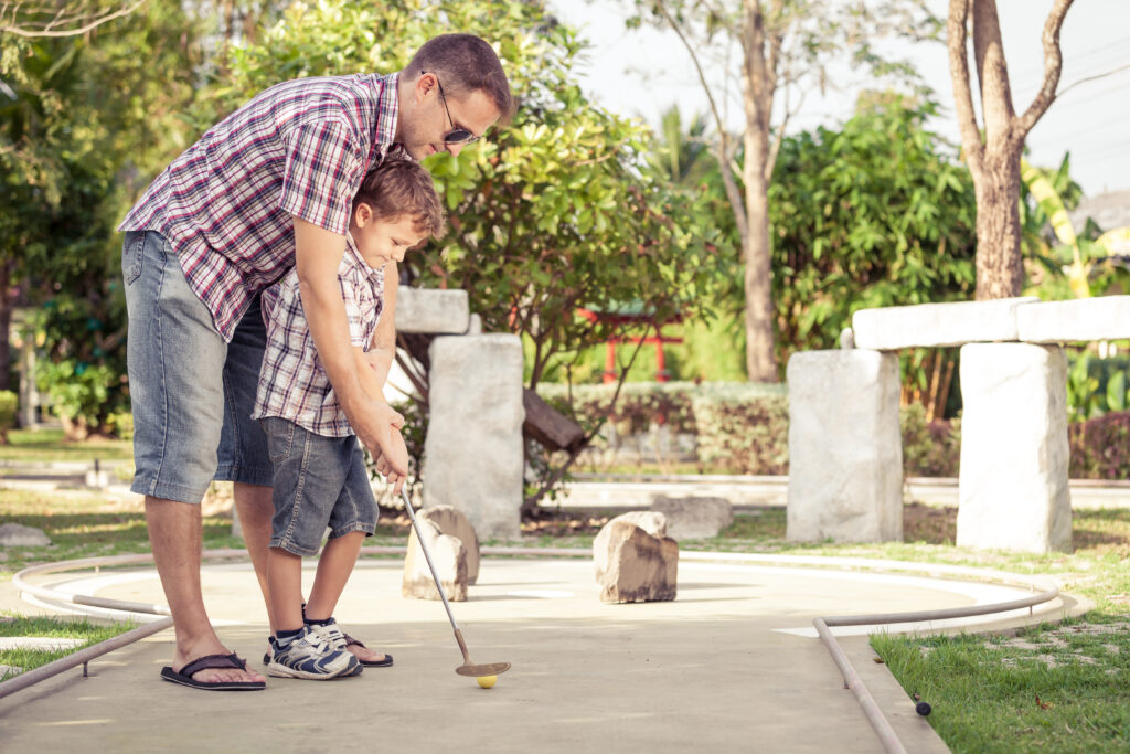 dad-teaching-son-to-putt-mini-golf