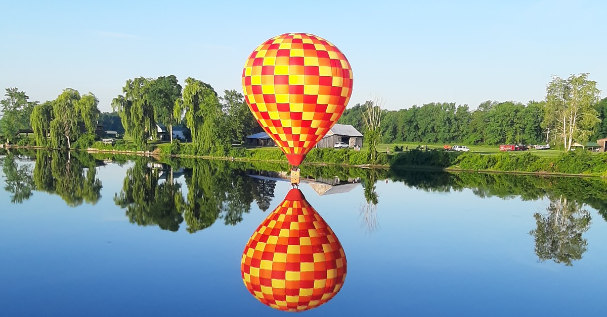 hot-air-balloon-flying-over-lake-and-reflected-in-the-water