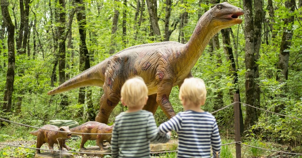 two-boys-at-dinosaur-park-with-life-size-dinosaur-figures