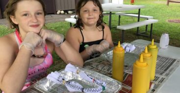 two young female campers making tie dye t-shirts