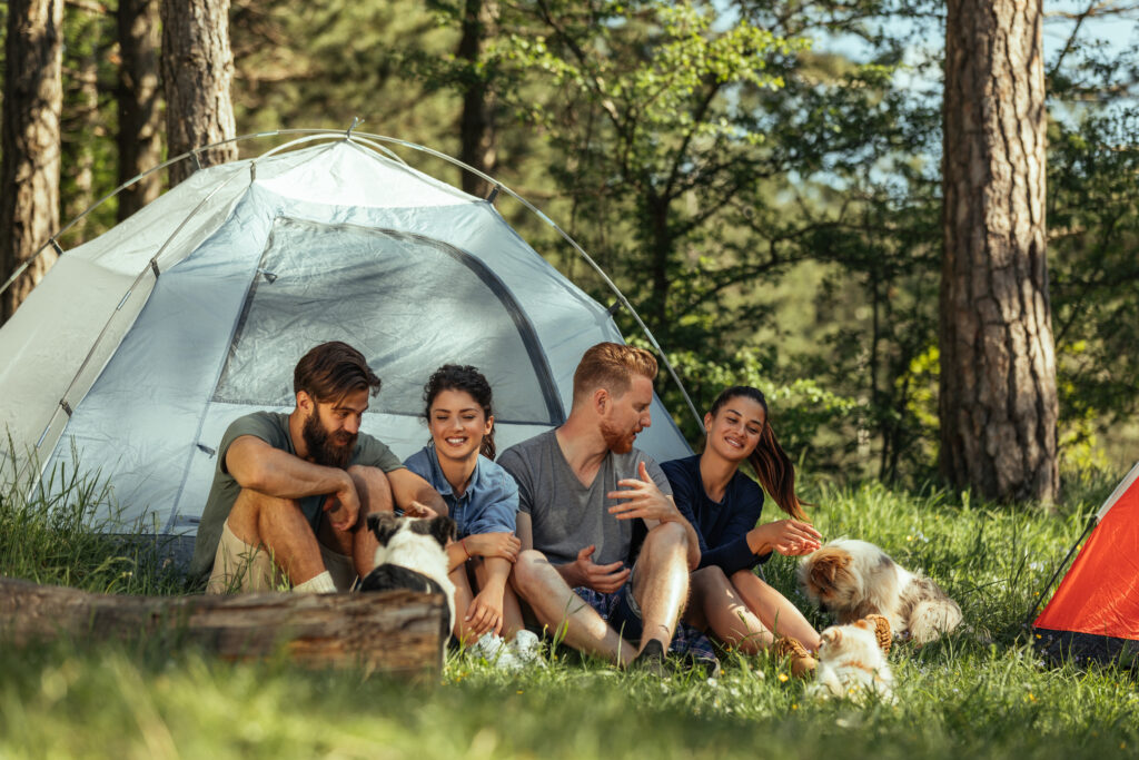 group of friends and dog tent camping in woods