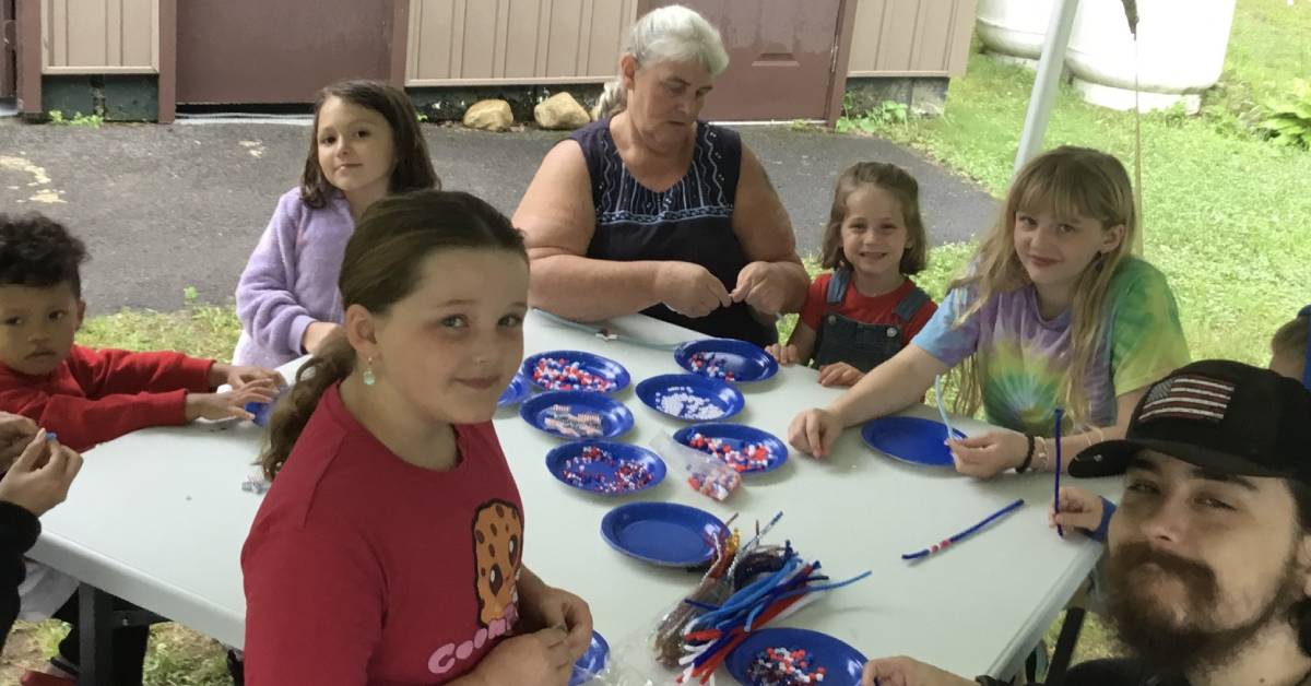 family around outdoor table does 4th of july crafts