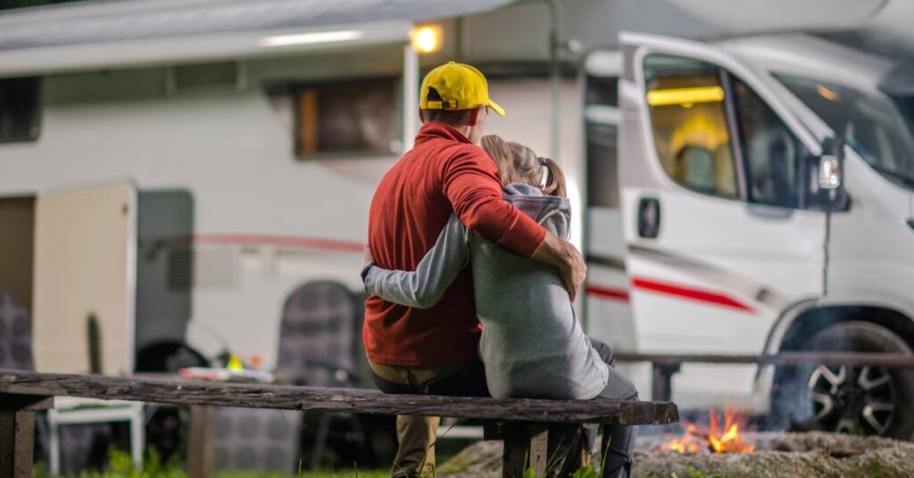 dad and daughter hug on bench at rv campsite with fire