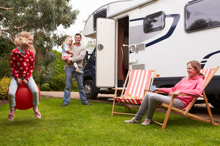 young family playing outside camper van