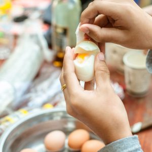 woman peeling hard boiled egg at campsite