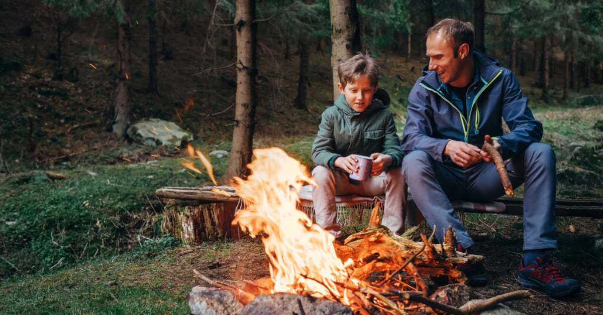 father and son sitting at a campfire