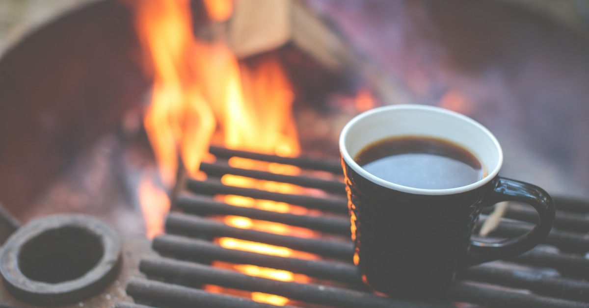 mug of coffee warming over a campfire