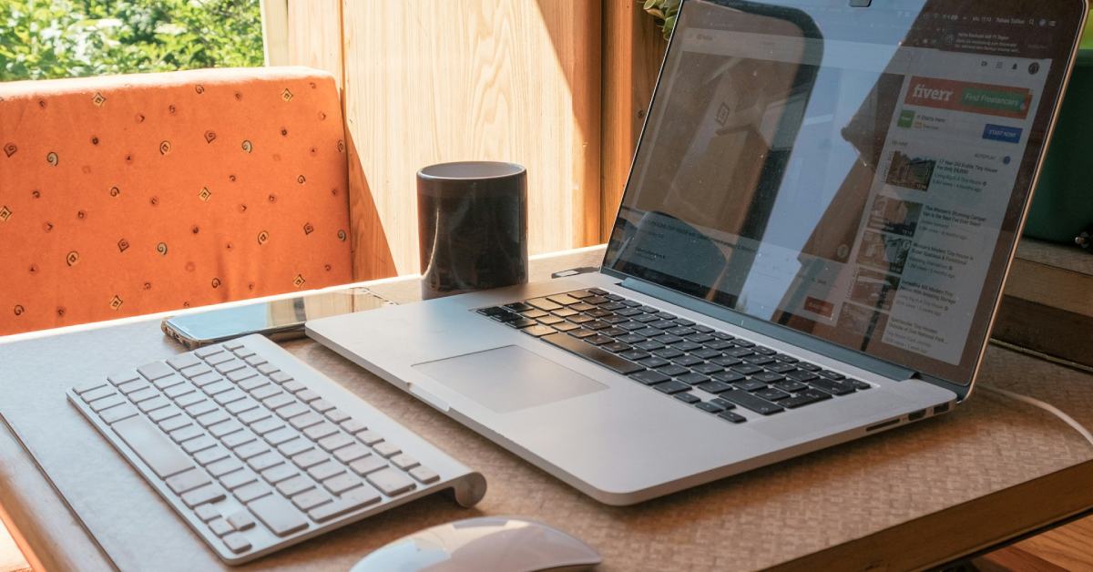 tiny desk space set up with a laptop, keyboard, mouse, and cup of coffee