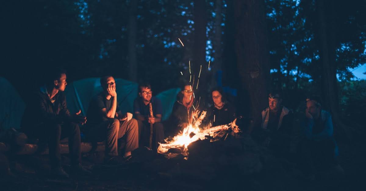 group of people sitting around a campfire