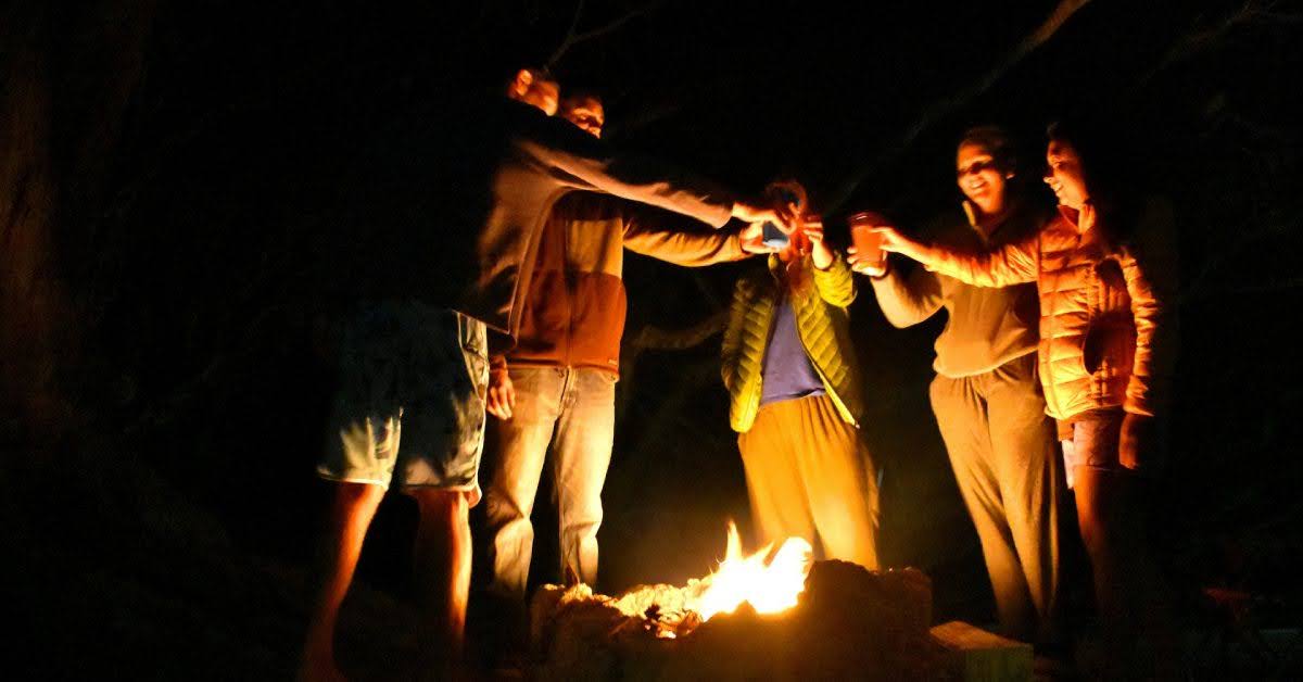 group of people cheersing over a campfire